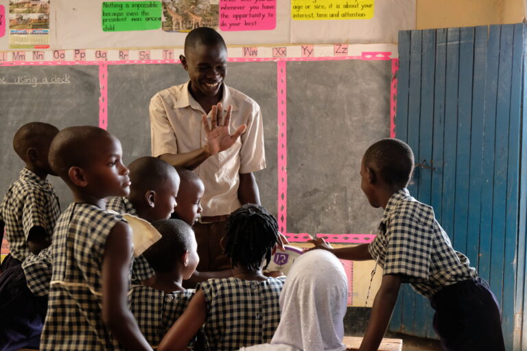A smiling teacher and a group of school children.