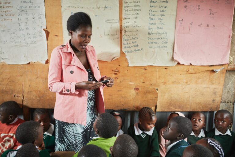 a teacher in a classrom holding a mobilde phone