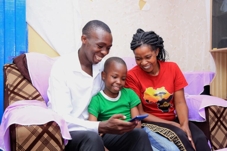 two adults and a child reading together on a mobile phone